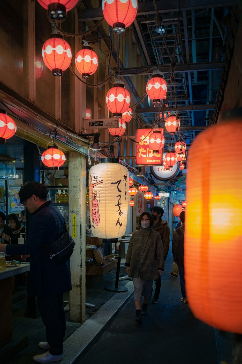 a group of people walking down a street under red lanterns
