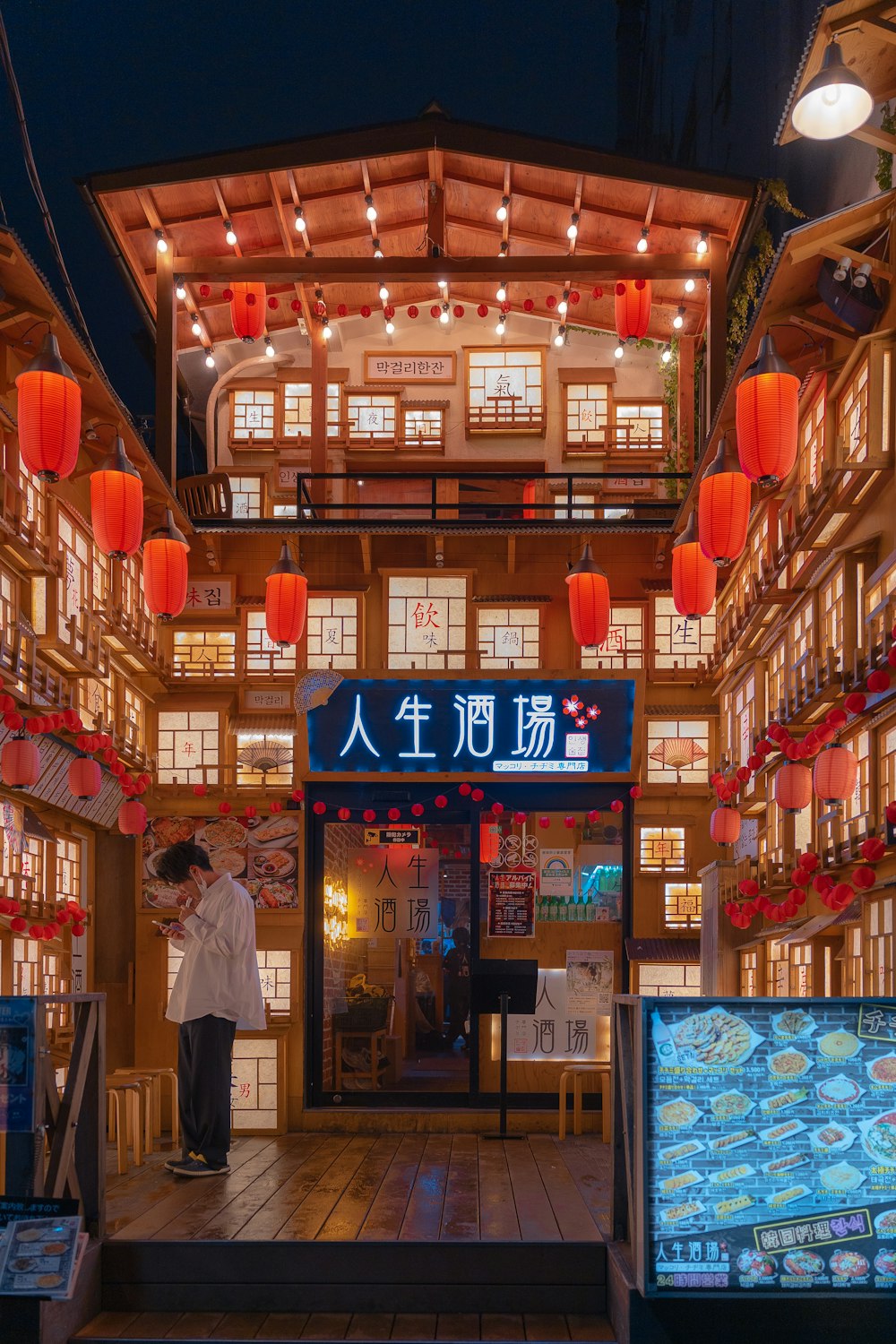 a man standing in front of a restaurant with red lanterns hanging from the ceiling