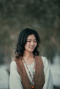 a woman wearing a brown vest and a beaded necklace