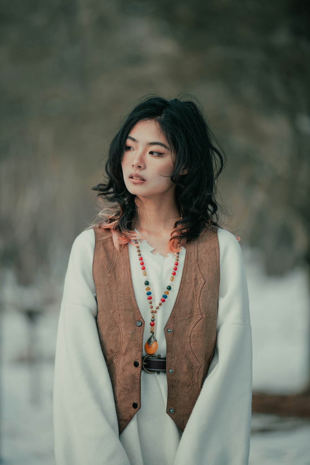 a woman wearing a sweater and a beaded necklace