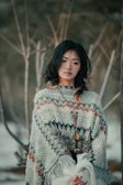 A vibrant poncho draped over a rustic wooden chair with Andean mountains in the background.