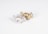 Two small animal figurines are positioned on a plain background. One is metallic silver and the other is metallic gold. They appear to be stylized representations of animals, possibly tigers or other big cats, with noticeable decorative patterns on their bodies.
