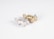 Two small animal figurines are positioned on a plain background. One is metallic silver and the other is metallic gold. They appear to be stylized representations of animals, possibly tigers or other big cats, with noticeable decorative patterns on their bodies.