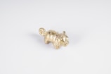 A small, golden animal figurine with detailed fur texture placed on a plain white surface. The figure appears to have a curled tail and upright ears.