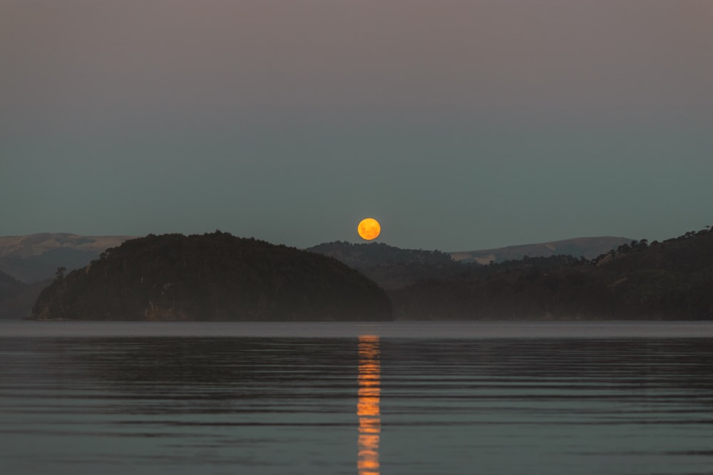 a full moon rising over a mountain range