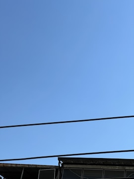 A panoramic view of a large commercial building equipped with lightning protection systems under a clear blue sky.