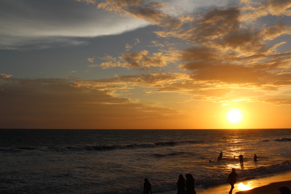 a group of people standing on top of a beach near the ocean