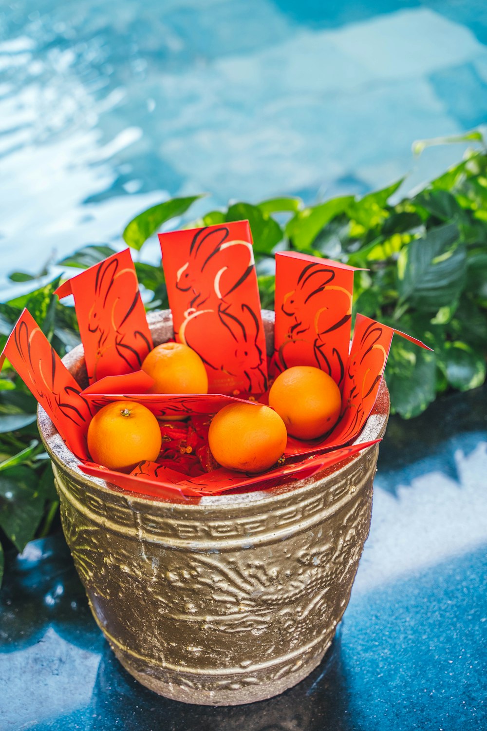 Un cesto di arance seduto su un tavolo accanto a una piscina