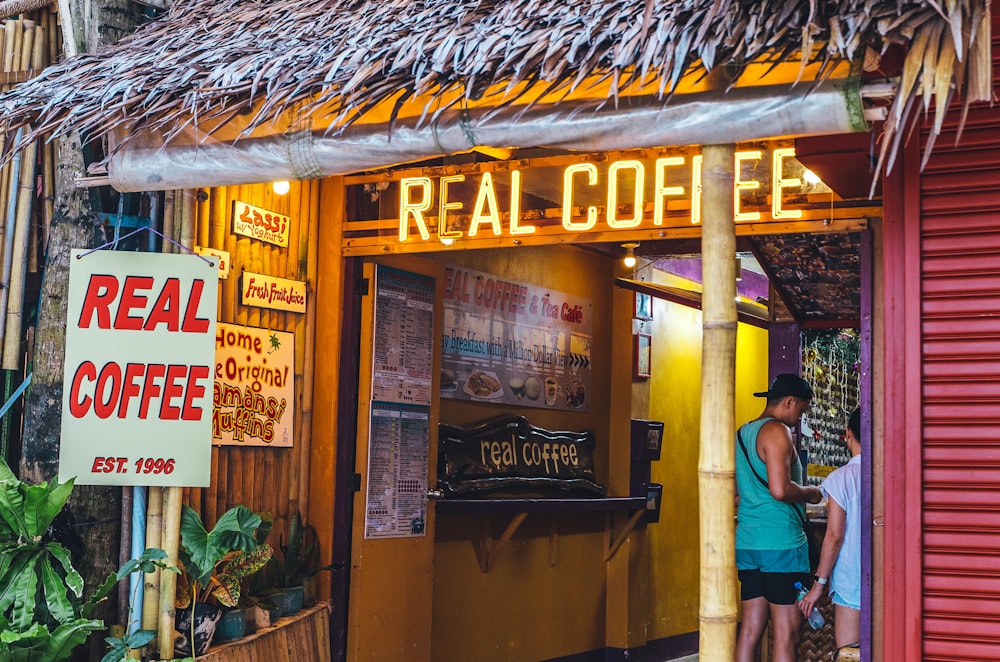 a couple of people standing outside of a coffee shop