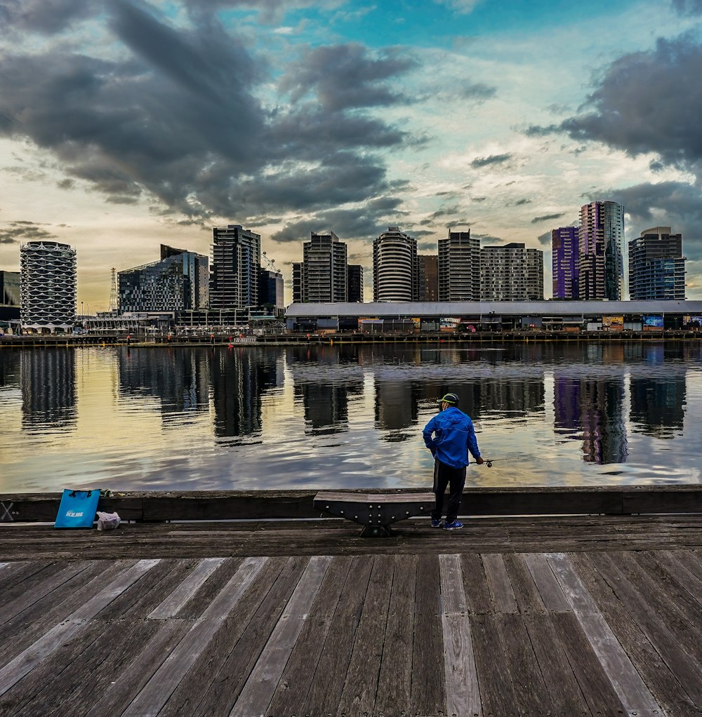 a man standing on a dock next to a body of water