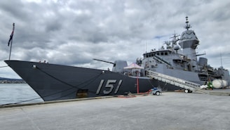 a large gray ship sitting next to a body of water