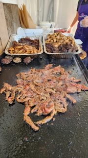 a table topped with trays of food covered in meat