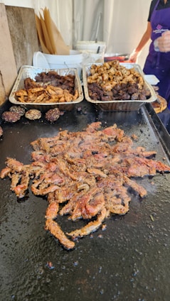 a table topped with trays of food covered in meat
