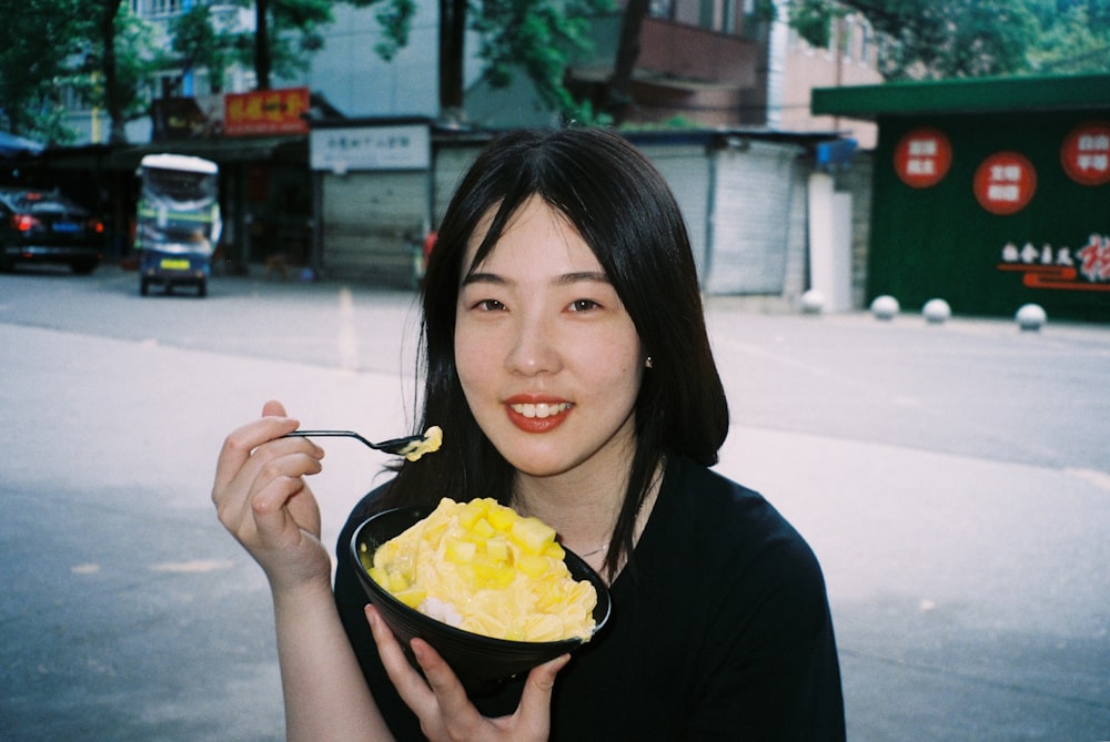 a woman holding a bowl of food and a spoon