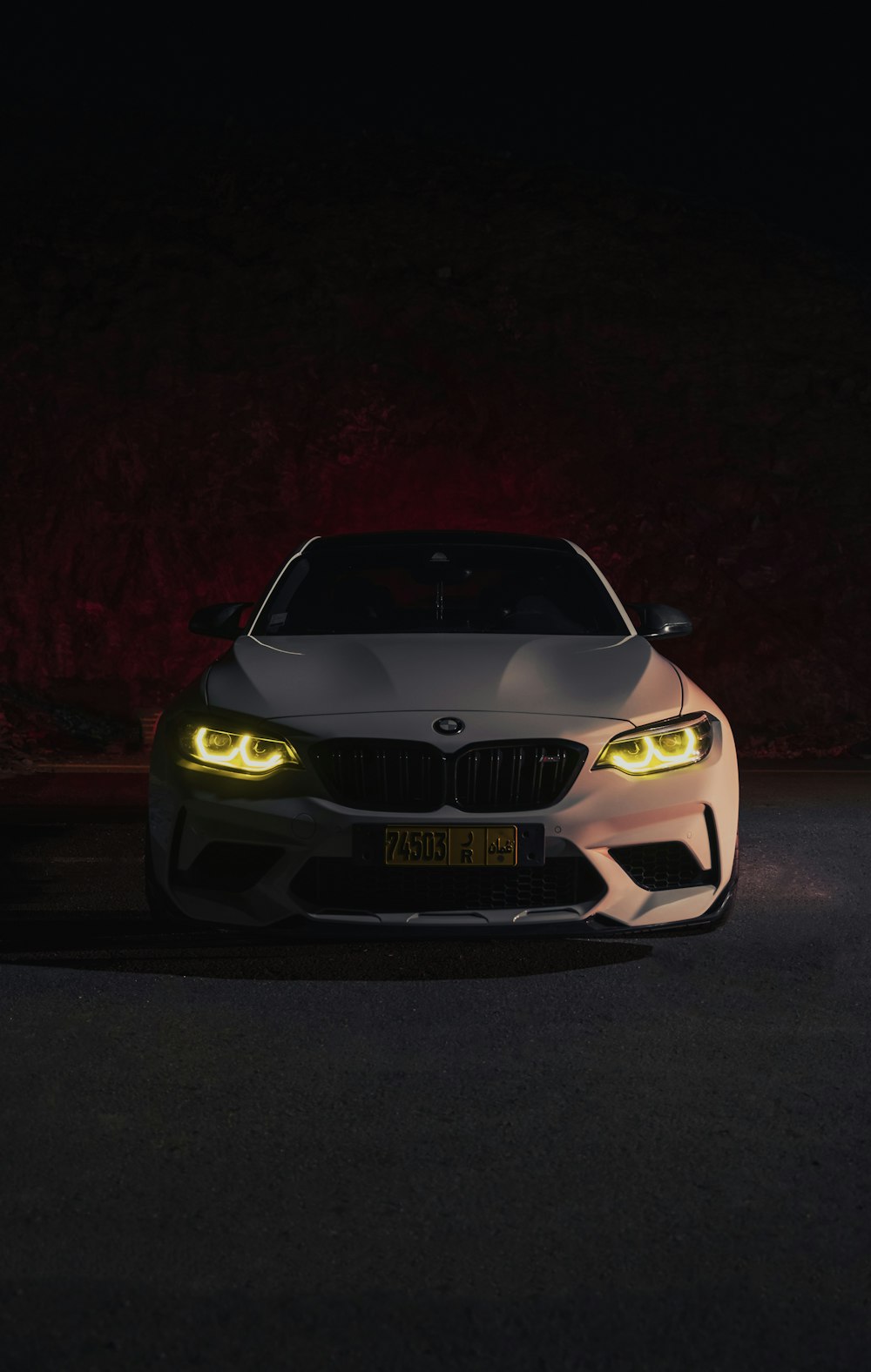 a white car with yellow eyes in the dark