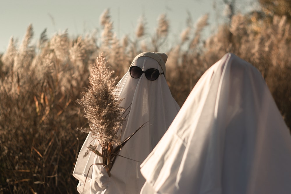 two people dressed in white walking through a field