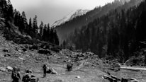 Group of hikers crossing a rocky mountain path with lush green valleys below.