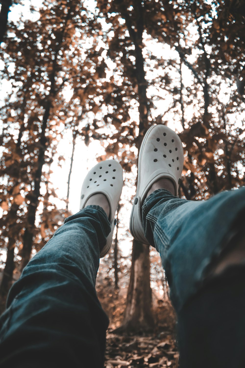 a person wearing white shoes standing in front of trees