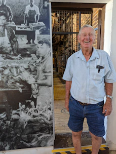 Photograph of a veteran industrial worker consulting with a younger team member on a factory floor.