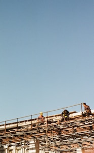 Construction workers collaborating on a Swiss building site with clear blue sky background.