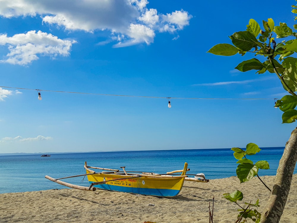 a yellow and blue boat sitting on top of a sandy beach