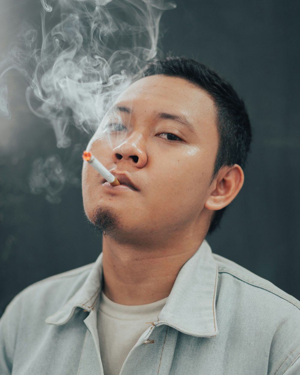 a man smoking a cigarette in front of a black background