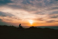 A group of bikers riding along a coastal highway at sunset.