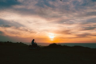 A group of bikers riding along a coastal highway at sunset.