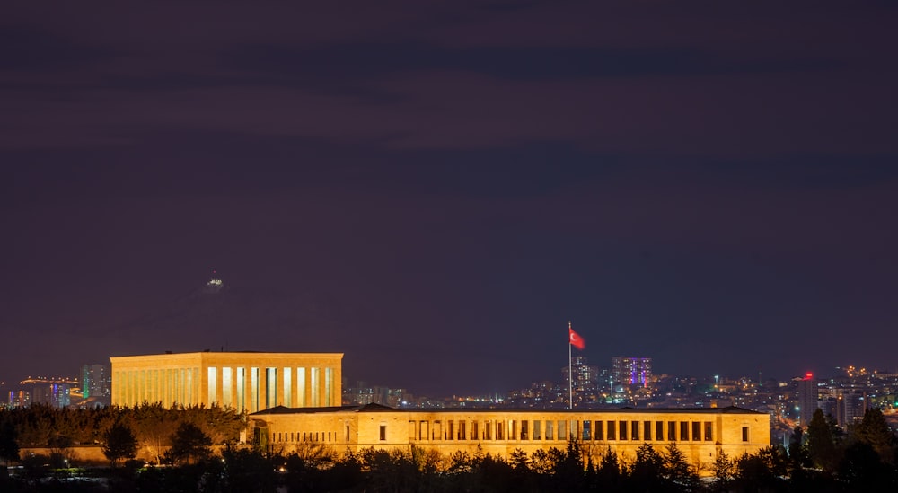 Eine Nachtansicht eines großen Gebäudes mit einer Stadt im Hintergrund