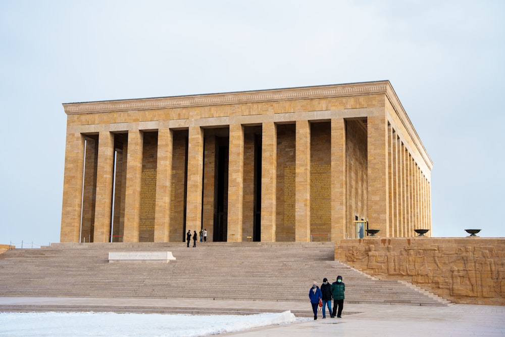 three people standing in front of a large building