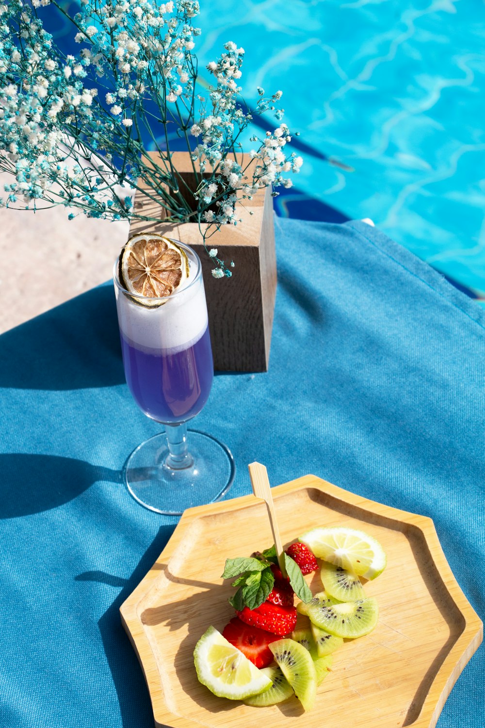 a plate of fruit on a table next to a pool