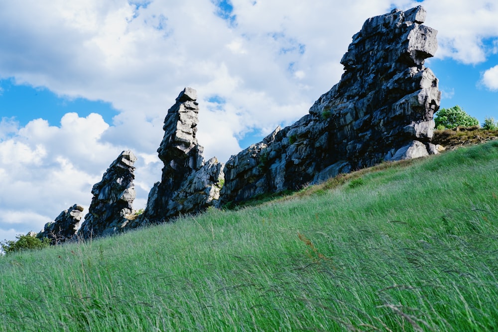 a group of rocks sitting on top of a lush green hillside