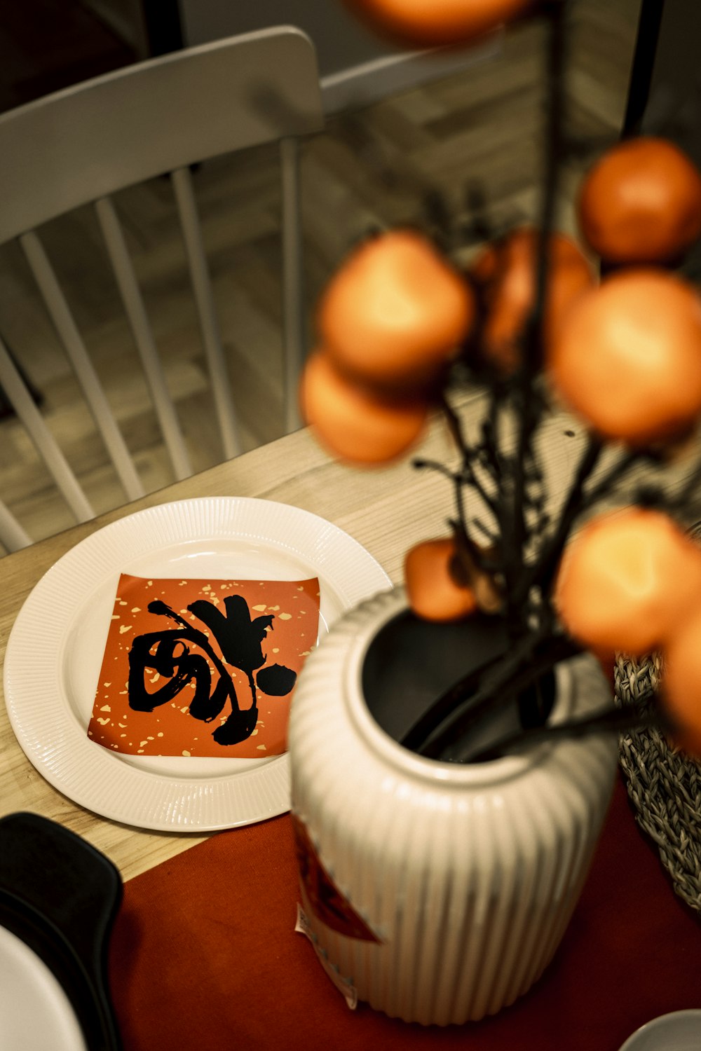 a white plate topped with a vase filled with oranges