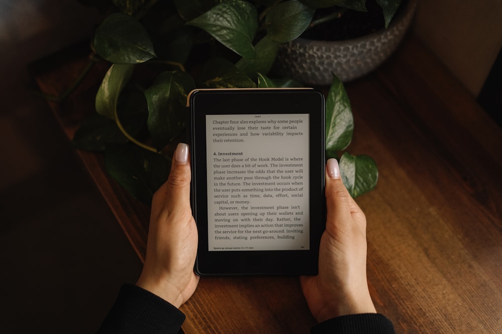 a person is holding a kindle on a table