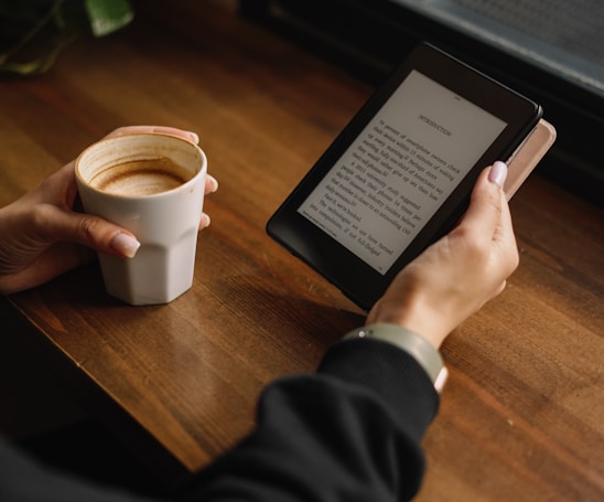 a person sitting at a table with a tablet and a cup of coffee