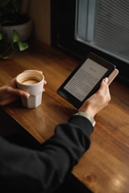 a person sitting at a table with a tablet and a cup of coffee