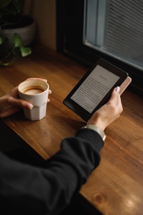 a person sitting at a table with a tablet and a cup of coffee