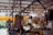 Plastic bags filled with various dry goods hang from hooks in an indoor market setting. The background is slightly blurred, showing other market stalls under a roof with lighting.
