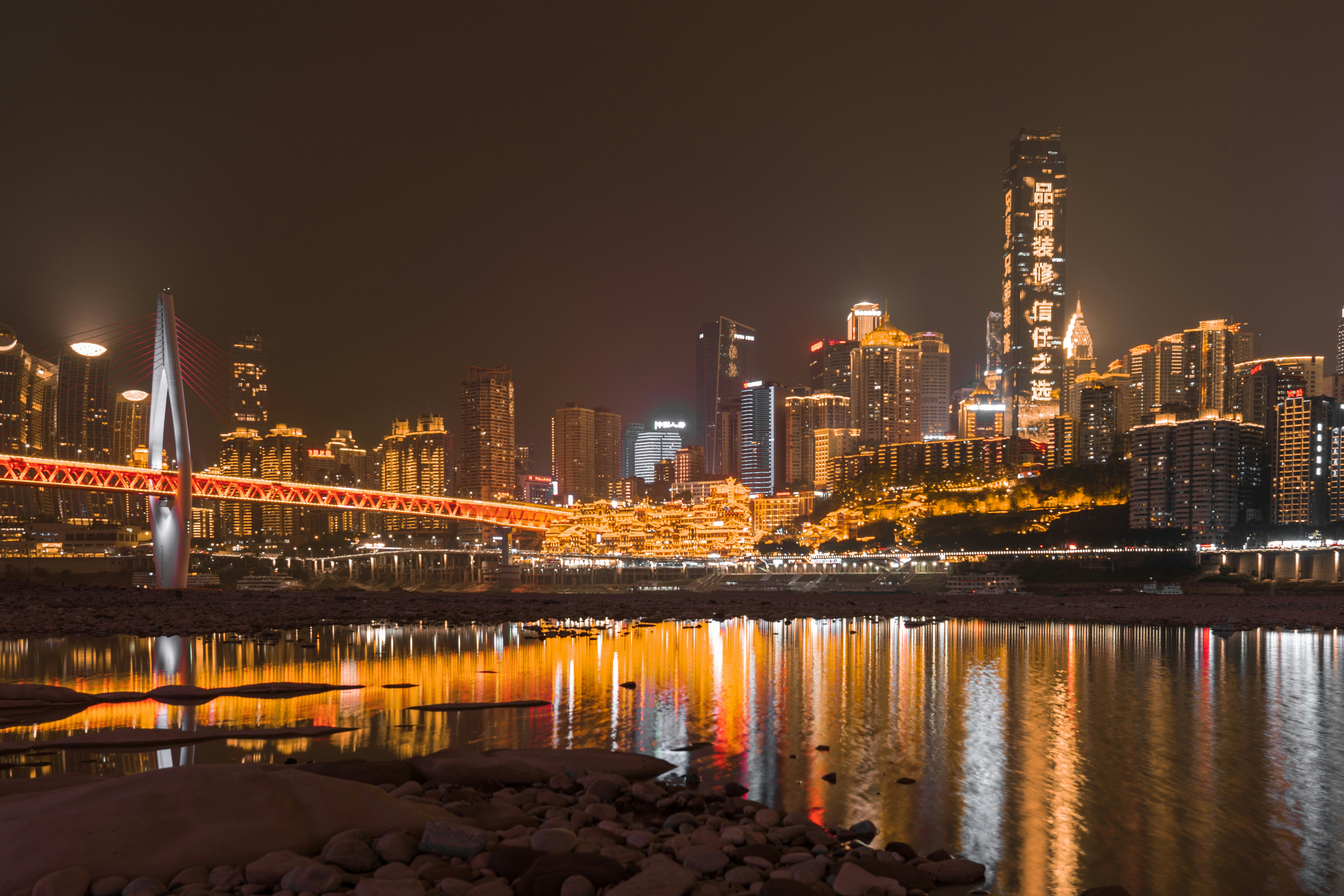 a city skyline at night with a bridge over a body of water