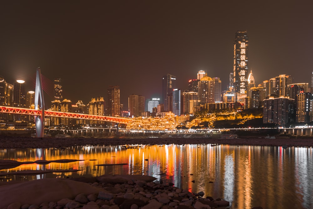 a city skyline at night with a bridge over a body of water