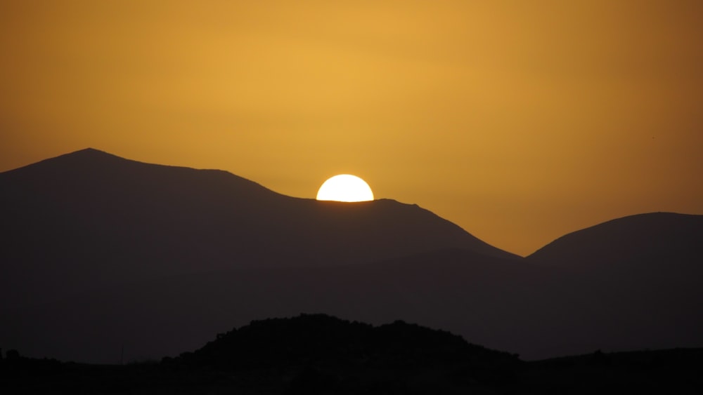 the sun is setting over a mountain range