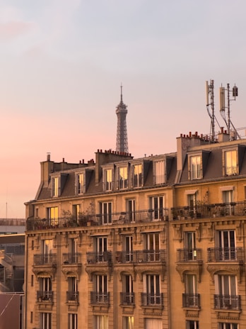 A cozy Parisian apartment balcony overlooking the Eiffel Tower at sunset, set for a private chef's dinner.