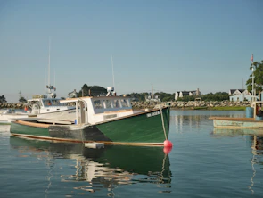 A sturdy Joshtek Marine boat cutting through calm blue waters near the harbor