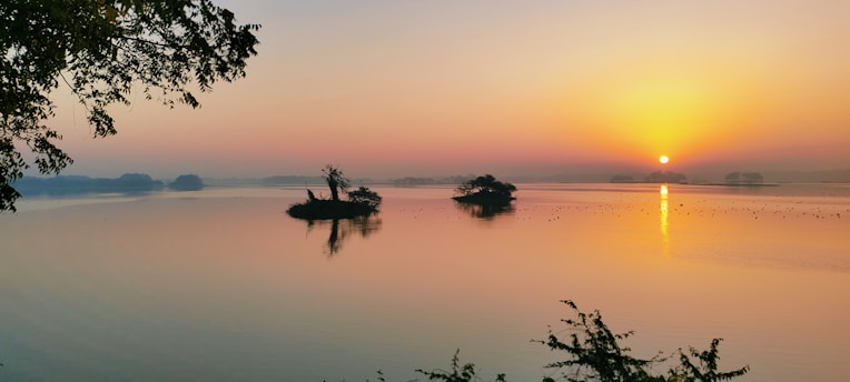 A serene sunrise over the lush, green hills of Namatoto island, with the calm sea reflecting the warm colors of dawn.