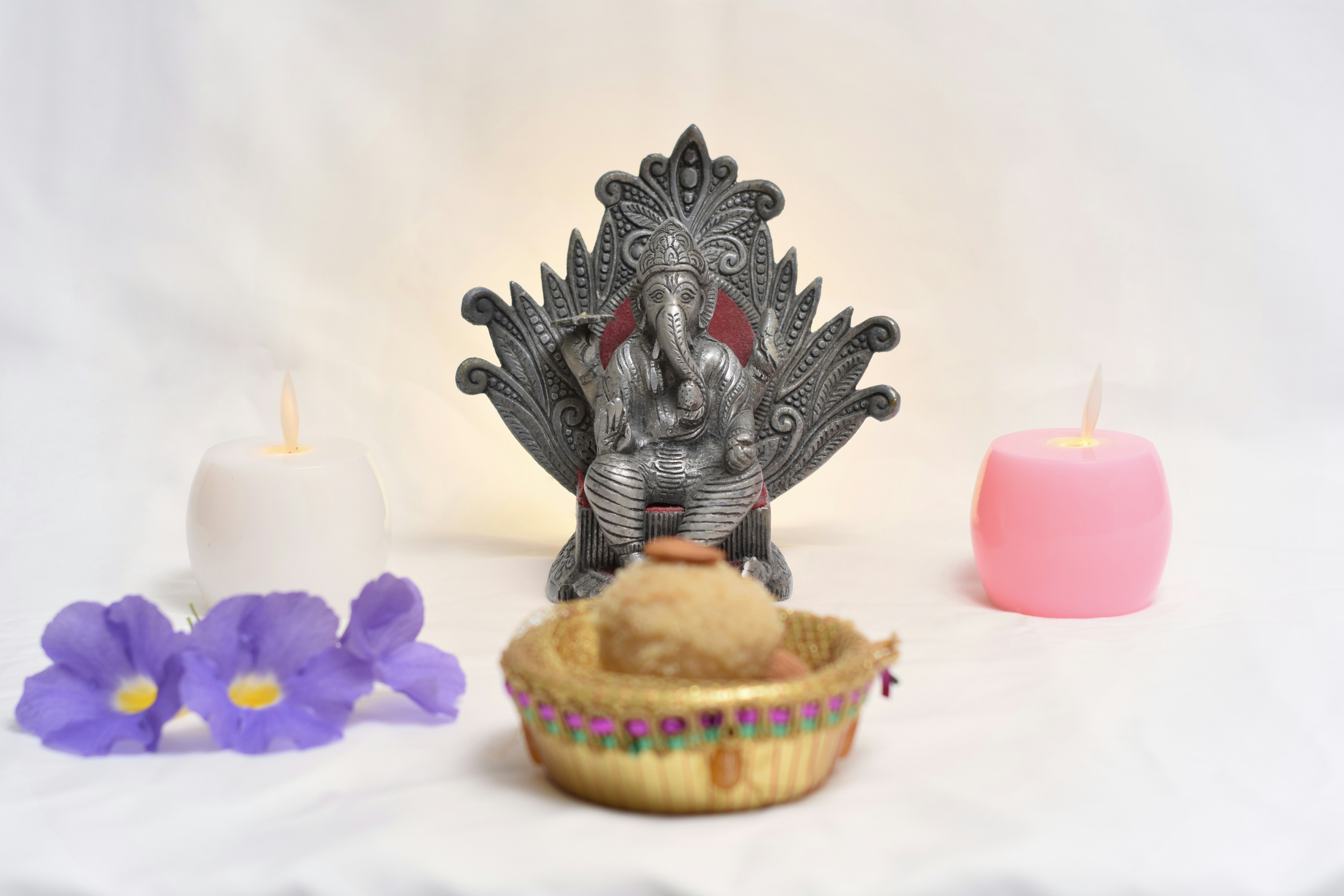 a statue of an elephant sitting on a chair next to a cupcake