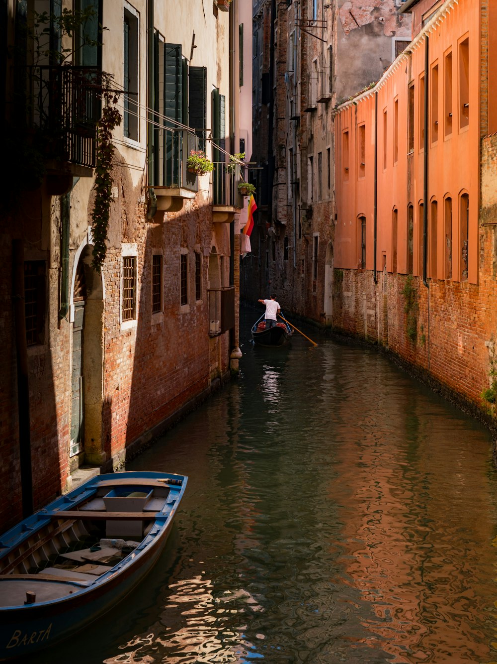 a small boat floating down a narrow canal between two buildings