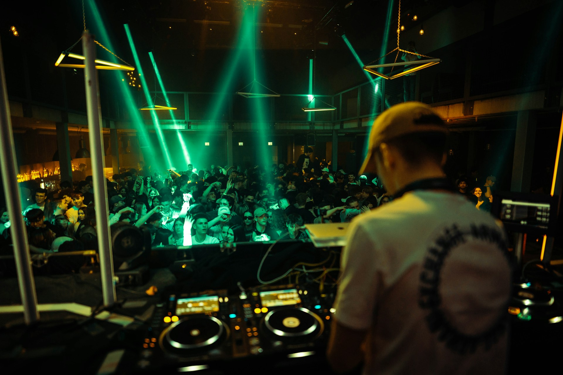 A DJ spinning electrifying tracks on stage, surrounded by an enthusiastic crowd at Club Lunar.