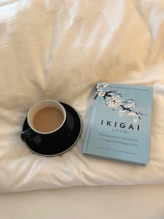 Close-up of the Absenteeism Iceberg book cover resting on a wooden desk with a coffee cup nearby.