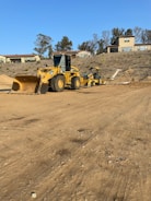 A civil engineer reviewing blueprints on a construction site with heavy machinery in the background