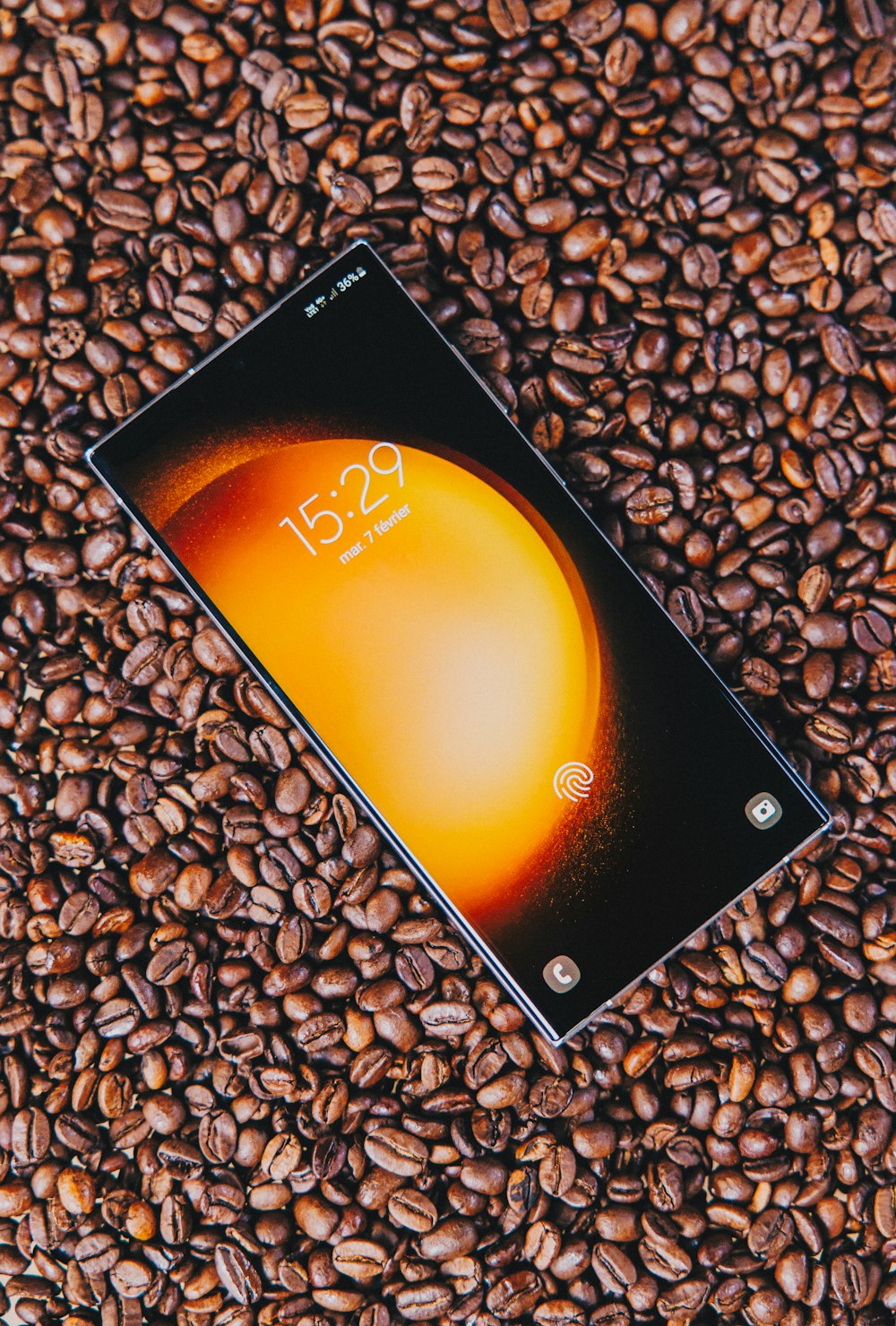 a cell phone sitting on top of a pile of coffee beans